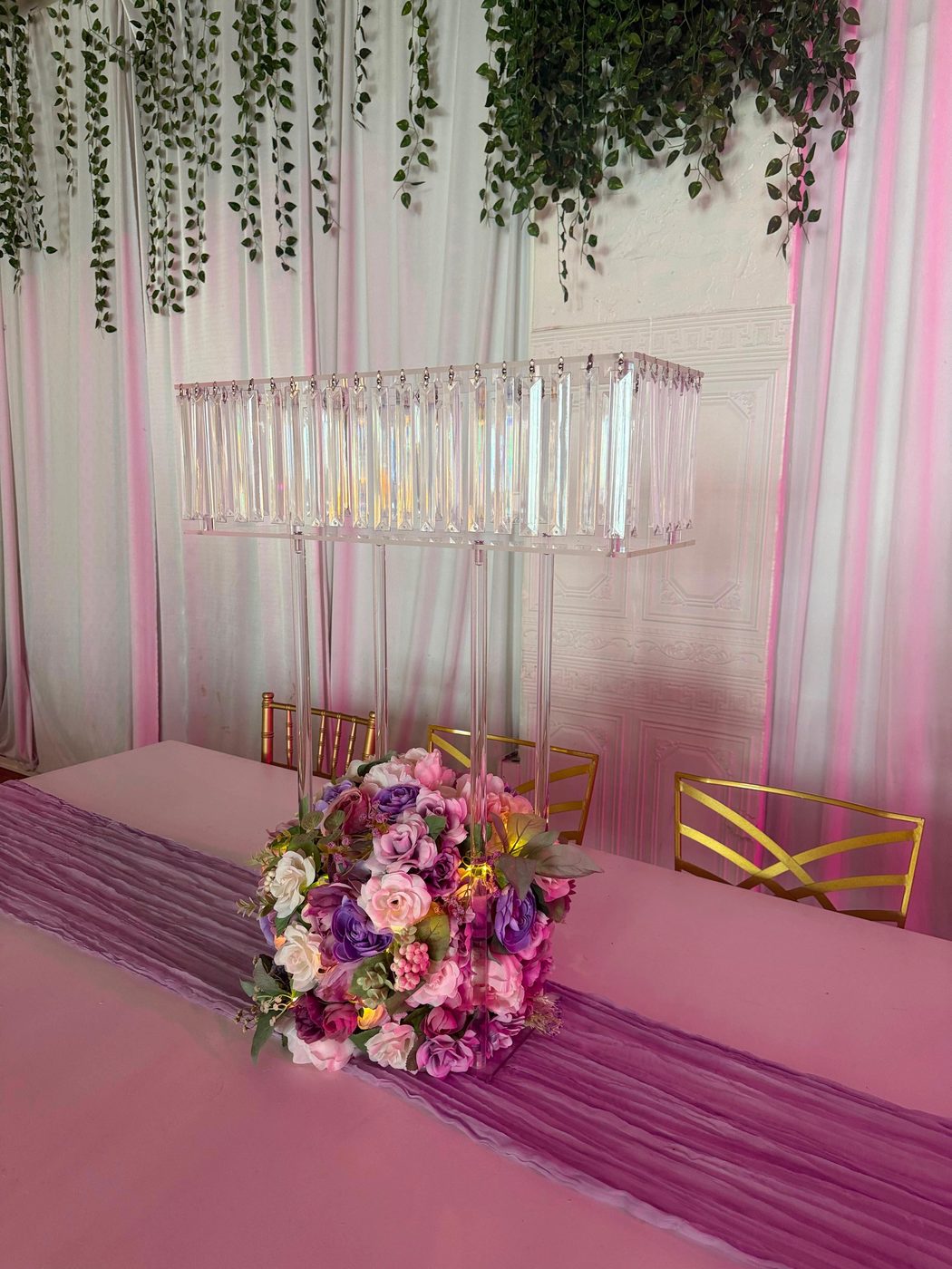 A blush table with a crystal centerpiece and a greenery canopy